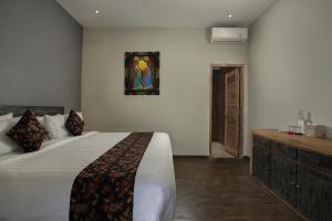 a bedroom with a large white bed and a dresser at MAHALONA BALI STAY in Canggu