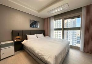 a bedroom with a large bed and a large window at Y Collection by UH FLAT Osiria in Busan