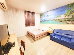 a living room with a blue couch and a painting at Royal Business Hotel in Nantou City