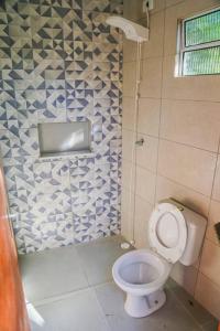 a bathroom with a toilet and a blue and white tiled wall at Casa da Cocanha COND com PISCINA-SINUCA-CHURRASQ-DECK com vista para o mar in Caraguatatuba