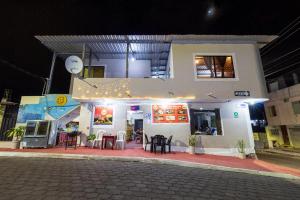 a white building with tables and chairs in front of it at Mí Oficina in Puerto Ayora