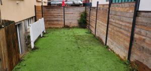 a backyard with a fence and a green yard at Tulsa Home - Superbe appartement de deux chambres - avec terrasse privée in Osny