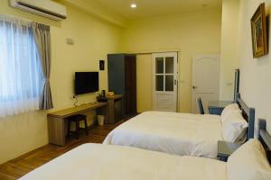 1 dormitorio con 2 camas, escritorio y TV en Country Road B&B en Guangfu