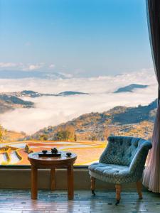 uma cadeira e uma mesa em frente a uma janela em The Twelve Manor•Terraces Lodge em Yuanyang