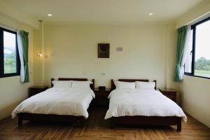 two beds in a room with two windows at Country Road B&B in Guangfu