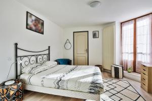 a bedroom with a large bed with white walls at Maison Saint-Thomas in Cuiseaux