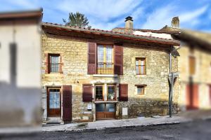 una vecchia casa in pietra con porte e finestre in legno di Maison Saint-Thomas a Cuiseaux