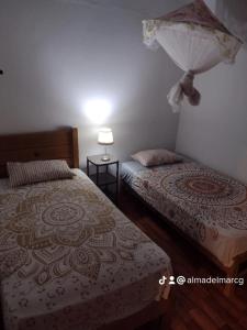 a bedroom with two beds and a lamp on the wall at Alma del mar caleta Grau in Tumbes