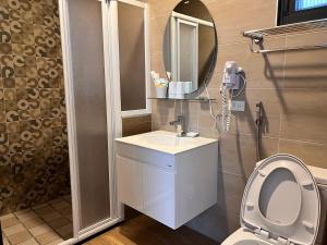 un bagno con un water, un lavandino e uno specchio di Country Road B&B a Guangfu