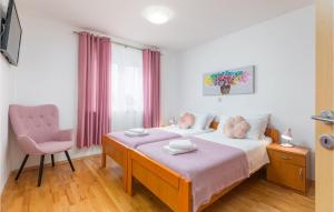 um quarto com 2 camas e uma cadeira rosa em Lovely Apartment In Valbandon With Kitchen em Fažana
