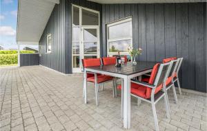 Nice Home In Haderslev With 3 Bedrooms, Sauna And Wifi في Flovt: طاولة غرفة الطعام مع كراسي حمراء على الفناء
