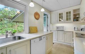 a kitchen with white cabinets and a sink and a window at Holiday Home Skovlindvej Iii in Marielyst