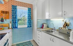 a kitchen with blue tiles and a sink and a window at Awesome Home In Fårevejle With Kitchen in Fårevejle +14 photos