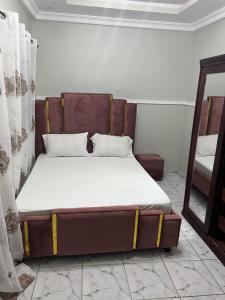 a bed sitting in a room with a mirror at Ladydie House in Douala
