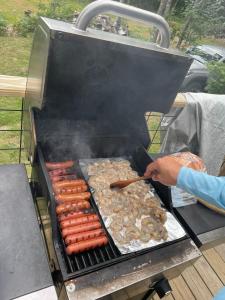 une personne qui cuisine des hot-dogs et des saucisses sur un grill dans l'établissement Da Knob on Lake Independence, 