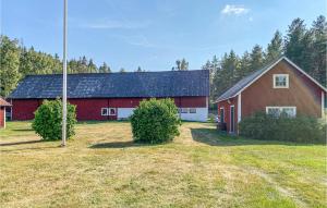 un granero rojo con un techo negro en un campo en Nice Home In Boxholm With Kitchen, en Boxholm