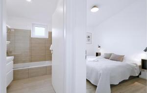 a white bedroom with a bed and a bath tub at Beach Front Home In Lembruchdümmer See in Lembruch