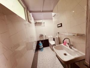 a white bathroom with a sink and a toilet at The Cocoon Camps & nature Resorts in Nainital