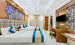 a hotel room with two beds and a television at Pine Tree Boutique Hotel in Chennai