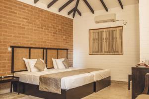 1 dormitorio con cama y pared de ladrillo en Tree of Life Nature Resort, en Kandy