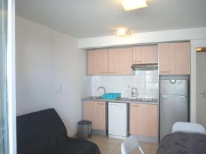 Elle comprend une petite cuisine avec des placards en bois et un réfrigérateur. dans l'établissement Appartement Marseillan-Plage, 2 pièces, 4 personnes - FR-1-387-74, à Marseillan