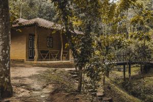 a small wooden cabin with a door in a forest at Tree of Life Nature Resort in Kandy