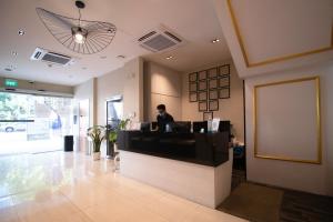 a woman standing at a counter in a lobby at Victoria Hotel a NuVe Group Collection in Singapore