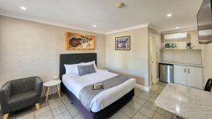 um quarto de hotel com uma cama e uma cadeira em Country Leisure Motor Inn em Dubbo