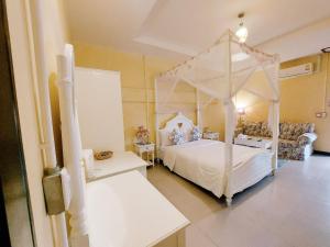 a bedroom with a white canopy bed and a couch at Retro Box Hotel Chumphon in Chumphon