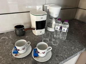 een aanrecht met twee koffiekopjes en waterflessen bij Demi's House in Volos