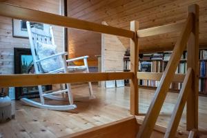 a wooden house with a staircase and a rocking chair at Chaloupka pod skalou in Libošovice