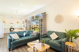 a living room with blue couches and a kitchen at Isla Villa, Cowes, Phillip Island. in Cowes