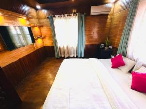 een slaapkamer met een wit bed met roze kussens bij Hostmandu B&B in Pātan