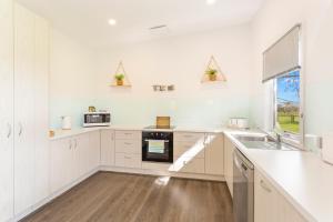 uma cozinha com armários brancos, um lavatório e uma janela em Isla Villa, Cowes, Phillip Island. em Cowes
