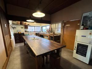 犬と泊まれる平屋Dog friendly house 黄昏 في Misaki: مطبخ مع طاولة خشبية كبيرة وثلاجة