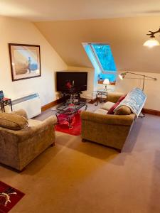 a living room with two couches and a flat screen tv at Red Stag Apartment in Nairn