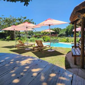 a group of chairs and umbrellas next to a pool at La Hacienda in uMhlali