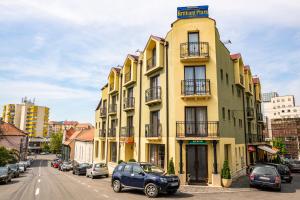 una macchina blu parcheggiata di fronte a un edificio giallo di Hotel Brilliant Plaza a Zalău