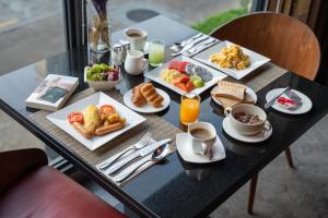 a table with plates of breakfast foods on it at Maitria Mode Sukhumvit 15 Bangkok - A Chatrium Collection in Bangkok