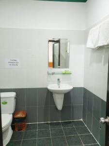 uma casa de banho com um lavatório, um WC e um espelho. em Mũi Dinh Hotel em Phan Rang-Tháp Chàm