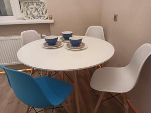 una mesa y sillas blancas con tazas y platillos en 1-ком.квартира от ИП Дома света, перекресток Кенесары-Кумисбекова, en Astana