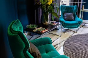 a living room with green chairs and a table at Hotel Brilliant Plaza in Zalău