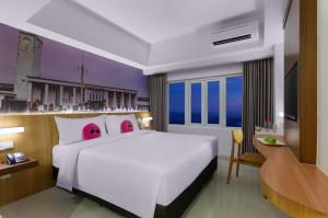 a bedroom with a large white bed and a television at favehotel Cilacap in Cilacap