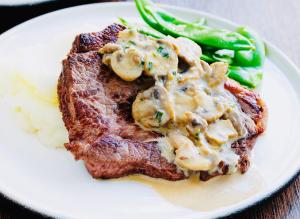 a white plate with steak and mashed potatoes and green beans at Arabian Palm Hotel in Rabigh
