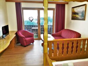 a living room with a red chair and a balcony at Romantik Appartements in Sankt Englmar