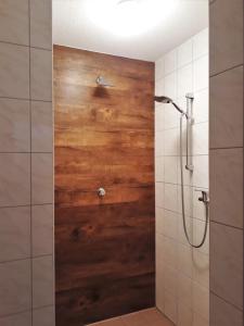 a bathroom with a shower with a wooden wall at Romantik Appartements in Sankt Englmar