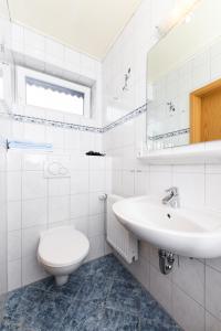 uma casa de banho branca com um WC e um lavatório em Hotel-Pension Marlies em Neuharlingersiel