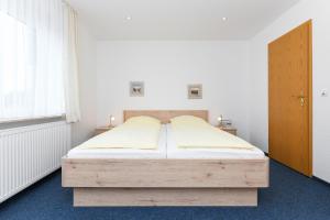 um quarto com uma cama de madeira num quarto em Hotel-Pension Marlies em Neuharlingersiel