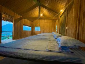 een groot bed in een kamer met houten wanden bij Mâm Xôi Homestay 