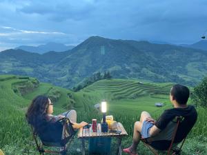 two people sitting at a table in chairs looking at a field at Mâm Xôi Homestay 